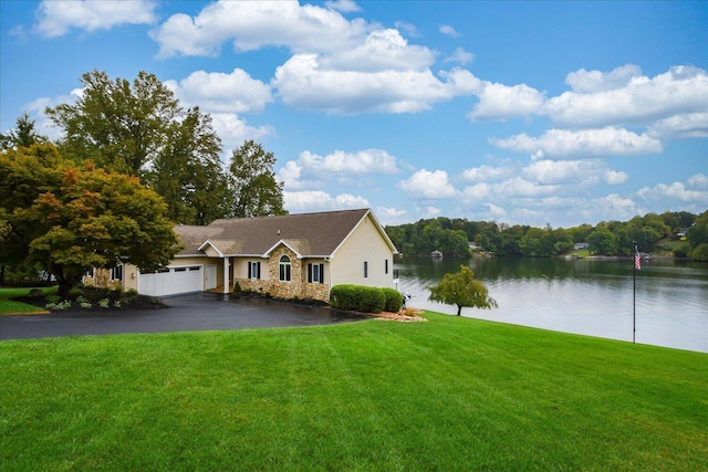 single story home featuring aphalt driveway, a garage, a water view, stone siding, and a front lawn