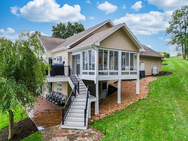 rear view of property featuring a yard, stairway, cooling unit, and a sunroom