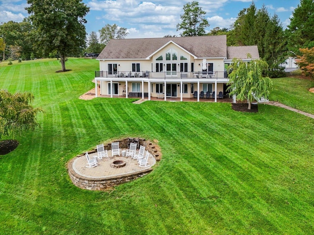 back of house featuring a fire pit, a deck, a lawn, and a patio area