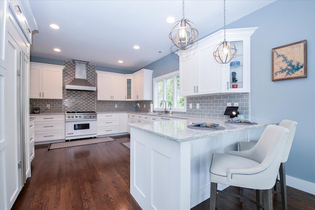 kitchen with wall chimney range hood, high end stainless steel range, glass insert cabinets, and white cabinets