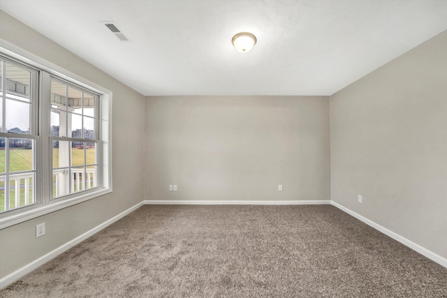 spare room with carpet flooring, visible vents, and baseboards