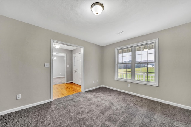 carpeted spare room with visible vents and baseboards