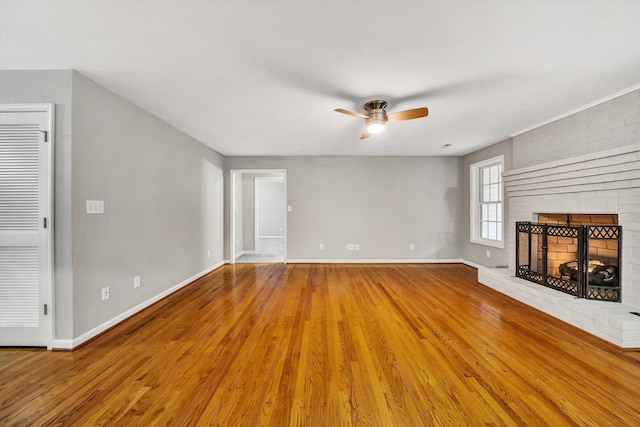 unfurnished living room with a ceiling fan, a fireplace, baseboards, and wood finished floors