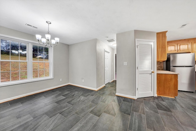 unfurnished dining area featuring baseboards, visible vents, and an inviting chandelier