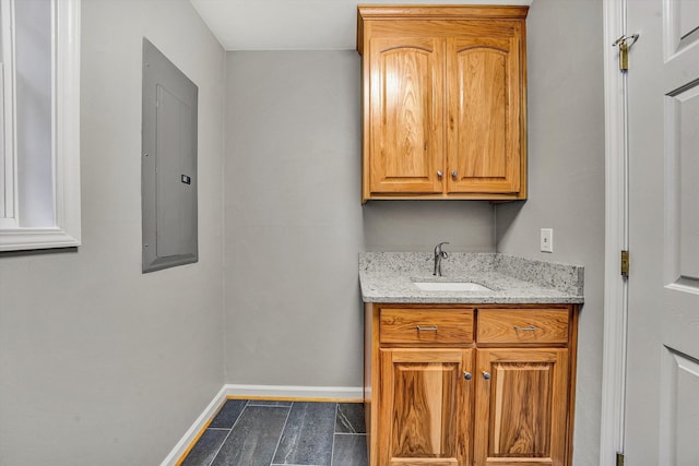 laundry room featuring a sink, electric panel, and baseboards