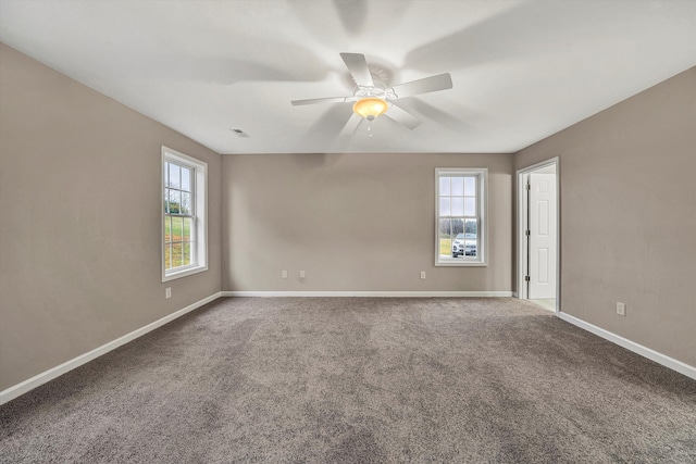 carpeted spare room with visible vents, baseboards, and a ceiling fan