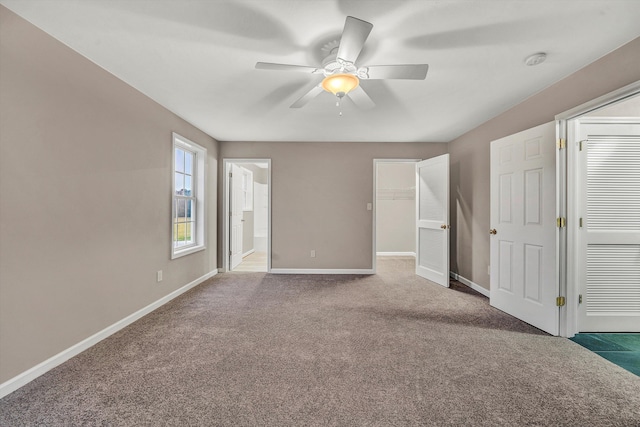 unfurnished bedroom featuring a closet, ensuite bathroom, a ceiling fan, carpet flooring, and baseboards