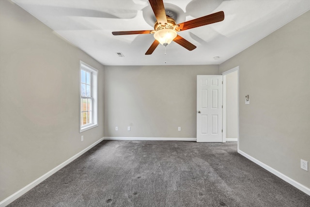 spare room featuring visible vents, dark carpet, baseboards, and ceiling fan