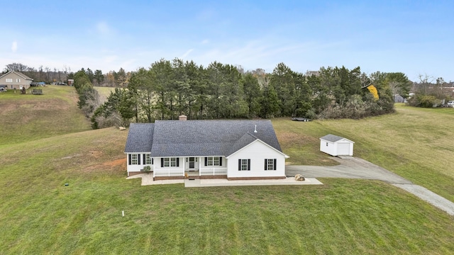 view of front of property with a shingled roof, an outdoor structure, a chimney, and a front lawn