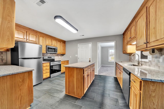 kitchen featuring stainless steel appliances, a kitchen island, a sink, visible vents, and light stone countertops