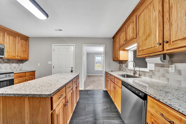 kitchen with stainless steel appliances, tasteful backsplash, a sink, light stone countertops, and baseboards