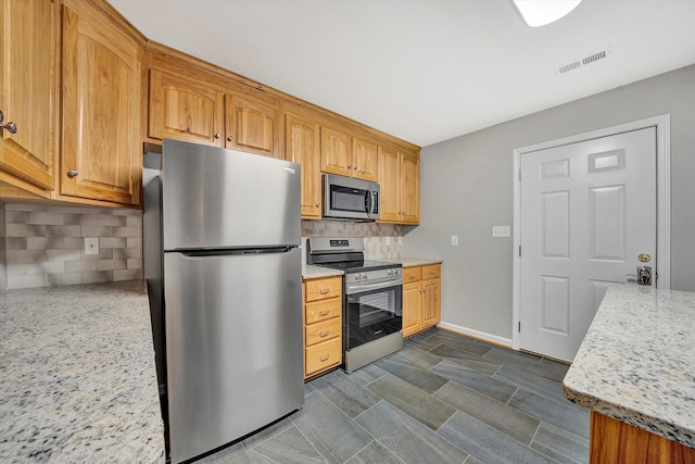 kitchen featuring light stone counters, visible vents, baseboards, appliances with stainless steel finishes, and decorative backsplash