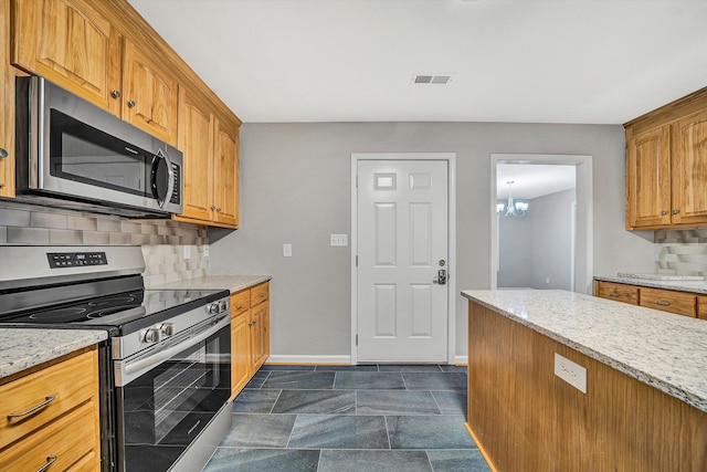 kitchen with baseboards, visible vents, light stone counters, stainless steel appliances, and backsplash