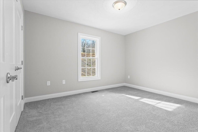 carpeted empty room with visible vents and baseboards