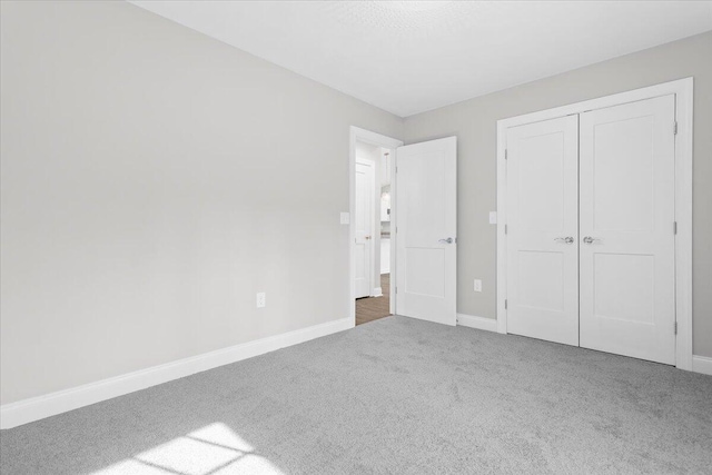 unfurnished bedroom featuring a closet, baseboards, and carpet