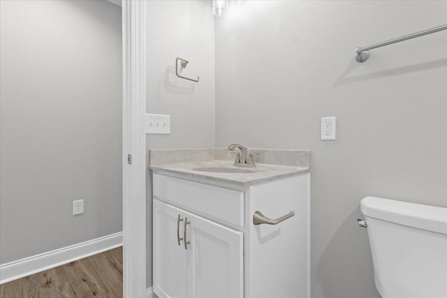 bathroom with vanity, toilet, wood finished floors, and baseboards