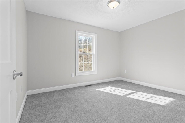 carpeted empty room with visible vents, baseboards, and a textured ceiling