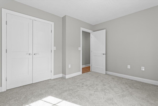 unfurnished bedroom featuring carpet flooring, baseboards, and a closet