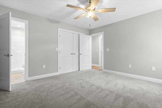 unfurnished bedroom with a closet, baseboards, carpet, and ensuite bath