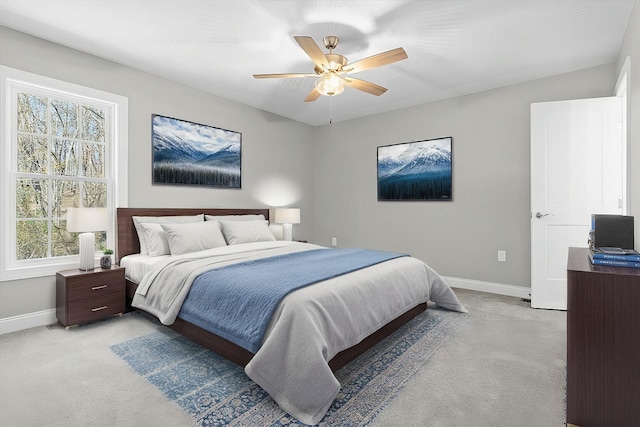 bedroom featuring a ceiling fan, light colored carpet, and baseboards