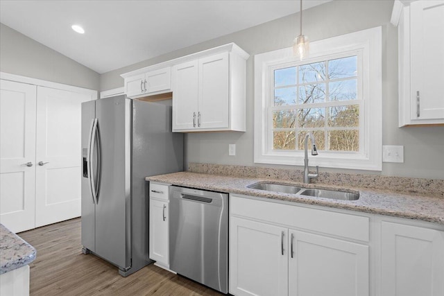 kitchen with lofted ceiling, light wood-style flooring, a sink, stainless steel appliances, and white cabinetry