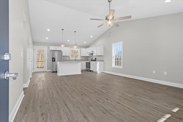 unfurnished living room with a sink, baseboards, ceiling fan, and wood finished floors