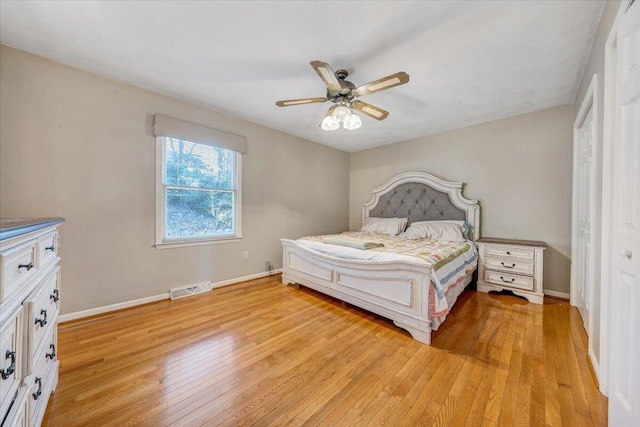 bedroom featuring baseboards, visible vents, ceiling fan, and light wood finished floors