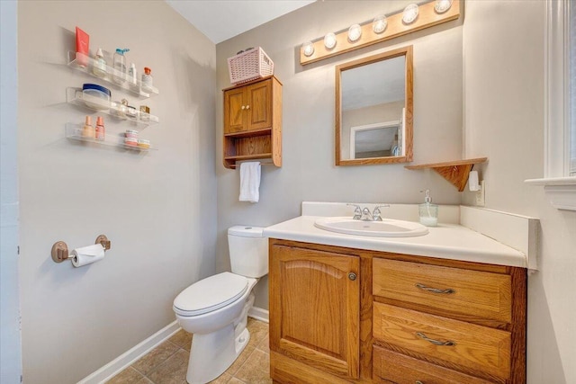 half bath featuring baseboards, vanity, toilet, and tile patterned floors