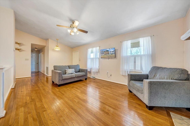 living room with lofted ceiling, ceiling fan, light wood-style flooring, visible vents, and baseboards