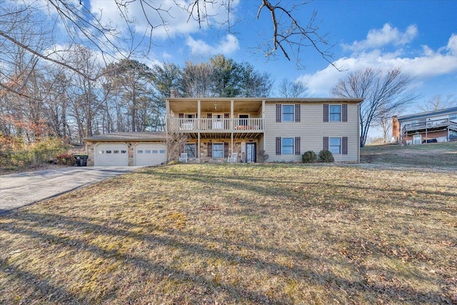 view of front of home with a chimney, a balcony, a garage, driveway, and a front lawn