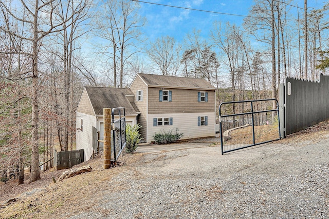 back of house with driveway, a gate, and fence