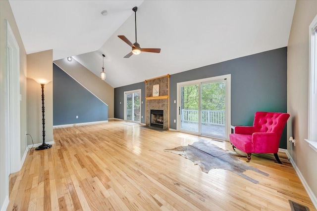 living area with ceiling fan, hardwood / wood-style flooring, a stone fireplace, and visible vents