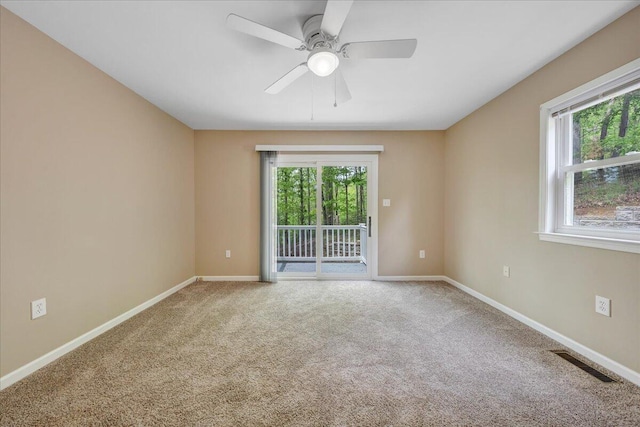 carpeted spare room with visible vents, baseboards, and ceiling fan