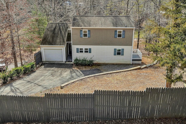 view of front of property featuring a shingled roof, fence, and driveway