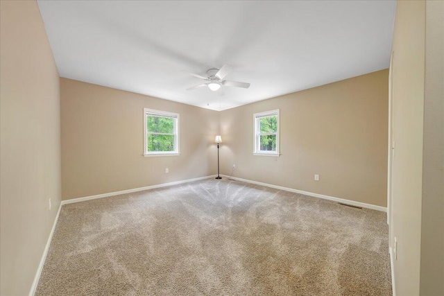 spare room with baseboards, ceiling fan, and carpet