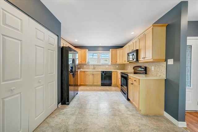 kitchen featuring light countertops, decorative backsplash, light brown cabinets, and black appliances