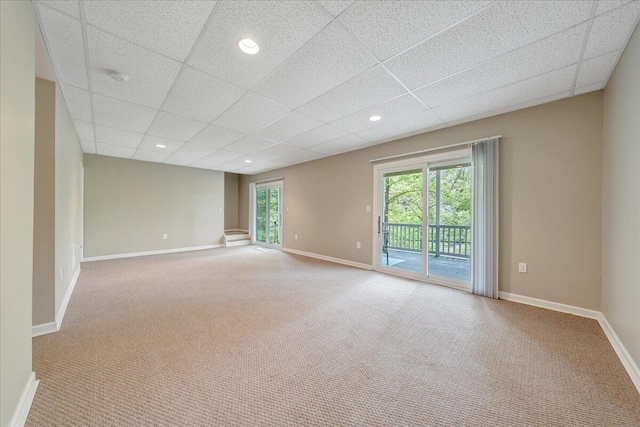 unfurnished room featuring carpet flooring, a drop ceiling, and baseboards