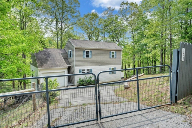 view of front of home featuring roof with shingles, an attached garage, fence, and a gate
