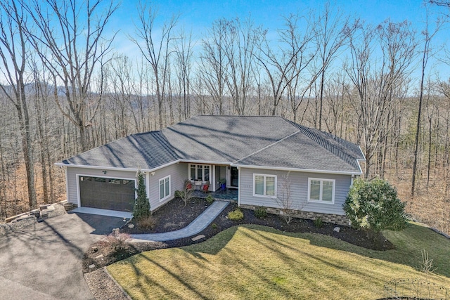 ranch-style home with an attached garage, driveway, a view of trees, and a front yard