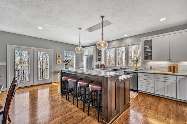 kitchen with a center island, stainless steel dishwasher, a sink, wood finished floors, and a kitchen breakfast bar