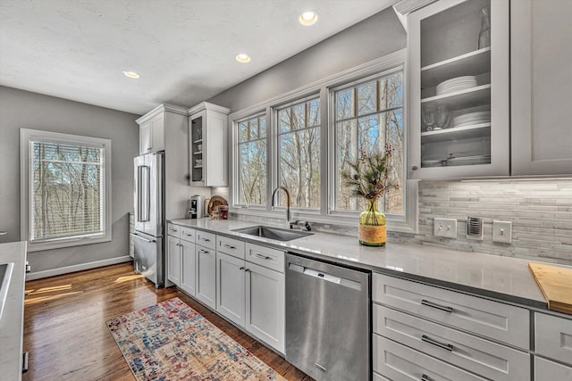 kitchen with glass insert cabinets, plenty of natural light, appliances with stainless steel finishes, and a sink