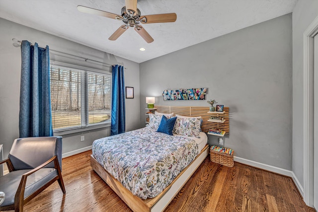 bedroom with ceiling fan, wood finished floors, and baseboards