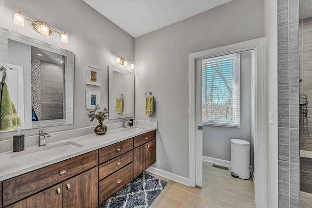 bathroom featuring double vanity, a sink, visible vents, and baseboards