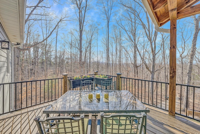 deck featuring outdoor dining space and a wooded view