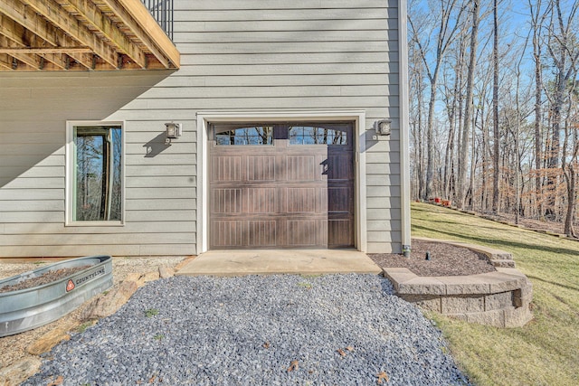 entrance to property with a garage, a yard, and gravel driveway