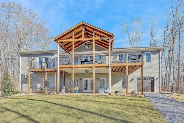 back of property with driveway, ceiling fan, an attached garage, a yard, and french doors