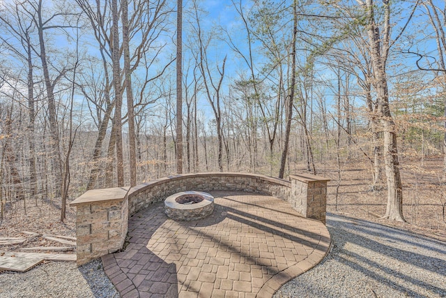 view of patio featuring a fire pit and a view of trees