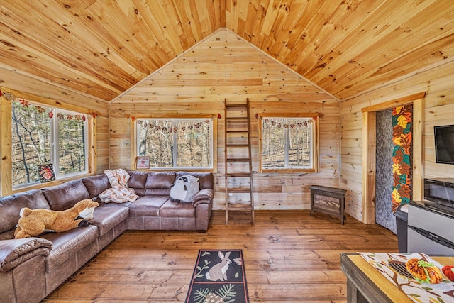 living area with wood-type flooring, vaulted ceiling, and wooden walls