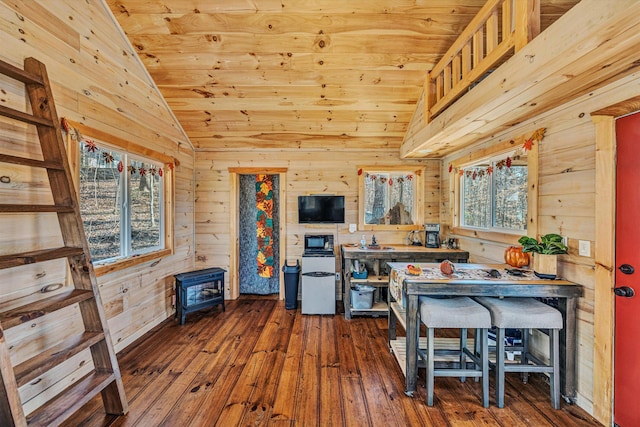 interior space with vaulted ceiling, dark wood-style flooring, wood ceiling, and wooden walls