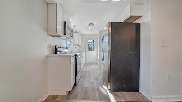 kitchen featuring light countertops, appliances with stainless steel finishes, white cabinetry, and light wood-style floors